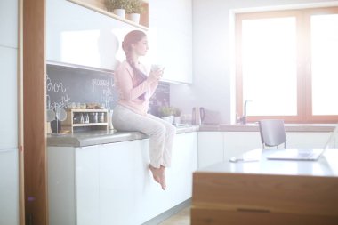 Mutfakta masada oturan genç kadın.