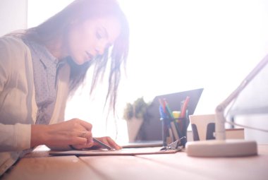 Masada oturan genç bir bayan. İş kadınıyım. Çizim. Öğrenci. İş yeri. Masa.