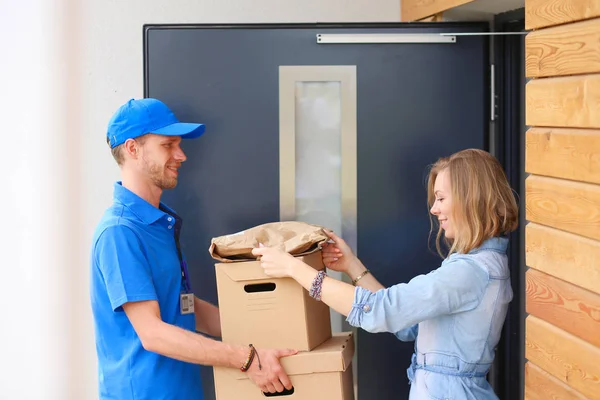 Усміхнений чоловік доставки в синій формі доставки посилок до одержувача - концепція кур'єрської служби. Усміхнений чоловік доставки в синій формі — стокове фото