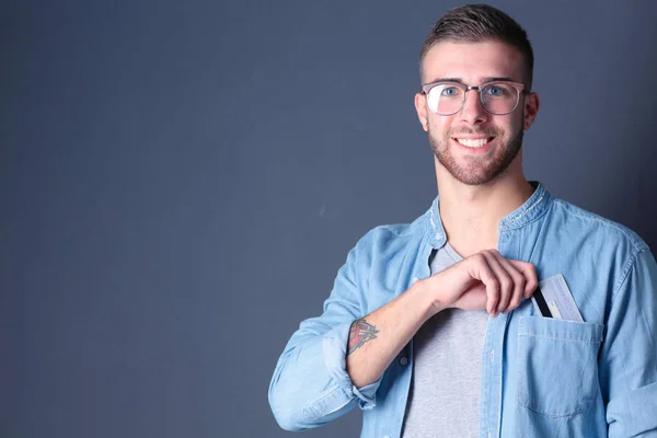 Young man holding a credit card standing on gray background. Young entrepreneur. — Stock Photo, Image