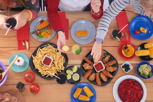 Vista superior do grupo de pessoas que jantam juntas enquanto estão sentadas à mesa de madeira. Comida na mesa. As pessoas comem fast food. — Fotografia de Stock