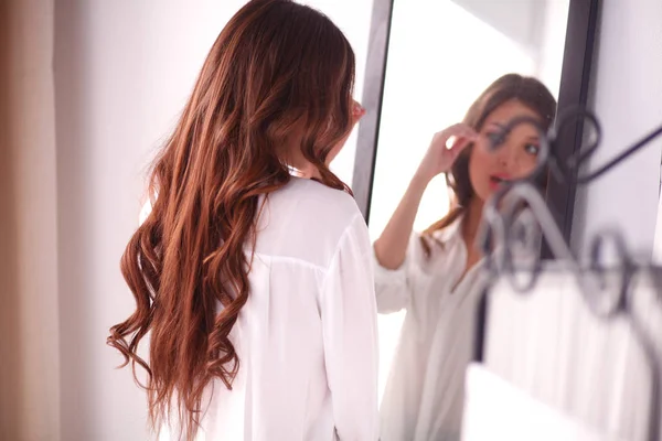 Young woman looking herself reflection in mirror at home. Young woman. — Stock Photo, Image