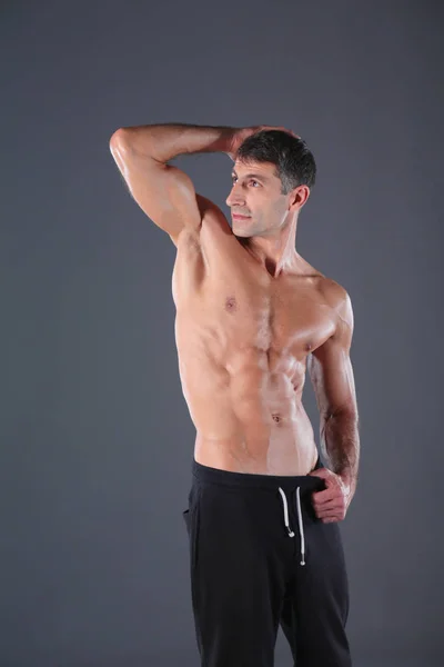 Muskulös man. Muskulös man på en grå bakgrund visar musklerna. Fitness-instruktör. Fitness professional. Träning. Mens fitness. — Stockfoto