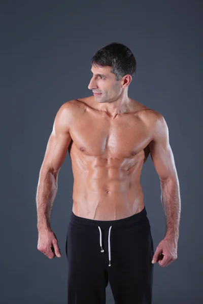 Hombre musculoso. Hombre musculoso sobre un fondo gris mostrando músculos. Instructor de fitness. Profesional de fitness. Entrenamiento. Aptitud para hombre . — Foto de Stock