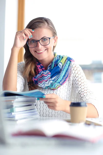 Jonge vrouw zit achter een bureau tussen de boeken. Studenten — Stockfoto