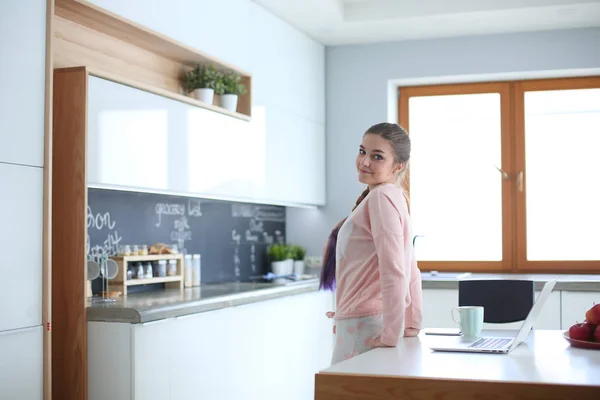 Mulher usando telefone celular de pé na cozinha moderna . — Fotografia de Stock