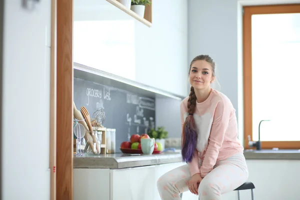 Mujer joven sentada en la mesa en la cocina . — Foto de Stock