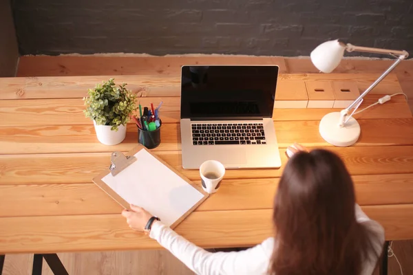 Portret van een ontspannen jonge vrouw die aan haar bureau zit met een kop koffie. Zakenvrouw. Werkplaats — Stockfoto