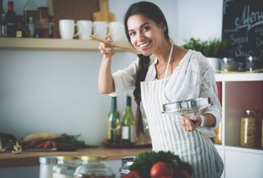 Mutfakta ahşap kaşıkla yemek pişiren kadın