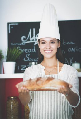 Genç bir kadın mutfağında ekmeği holding ayakta