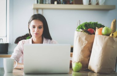 Gülümseyen kadın mutfakta tablet ve kredi kartı kullanarak alışveriş online