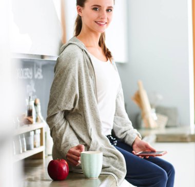 modern mutfakta otururken cep telefonu kullanan kadın.