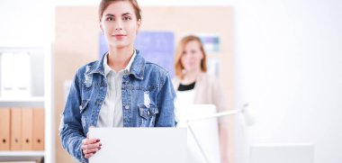 Masanın yanında duran iki genç kadın enstrüman, plan ve dizüstü bilgisayarla