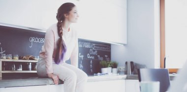 Mutfakta masada oturan genç kadın.