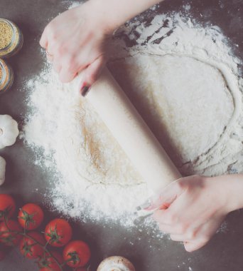 Güzel bir kadın mutfakta pasta pişiriyor. Masanın yanında duruyor..