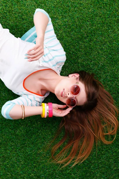 Beautiful redhead women lying down on green grass in summer time in the park