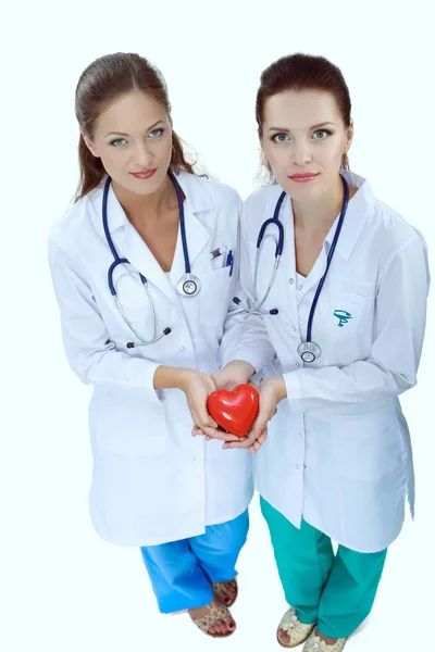 Dos doctora sosteniendo un corazón rojo, aislada sobre fondo blanco —  Fotos de Stock