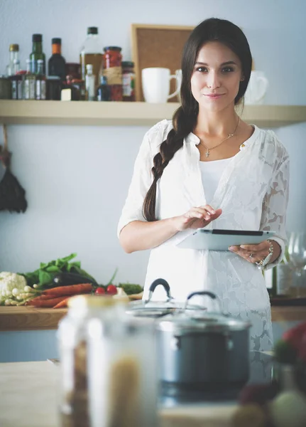 Junge Frau kocht mit Tablet-Computer in ihrer Küche — Stockfoto