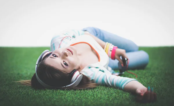 Ung kvinna Lyssna på musik, liggande på grönt gräs — Stockfoto