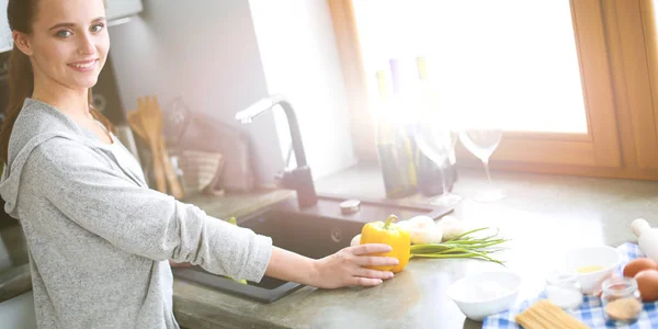 Vacker ung kvinna tvätta grönsaker till sallad stående i köket. — Stockfoto