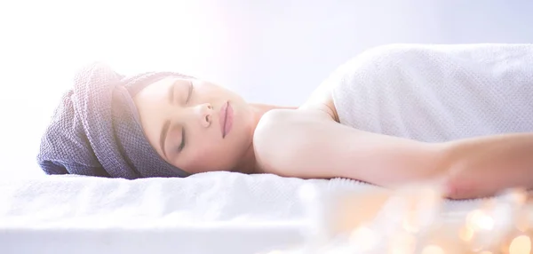 Jonge vrouw liggend op een massagetafel, ontspannen met ogen dicht — Stockfoto