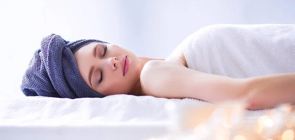 Jonge vrouw liggend op een massagetafel, ontspannen met ogen dicht — Stockfoto