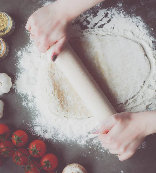 Güzel bir kadın mutfakta pasta pişiriyor. Masanın yanında duruyor..