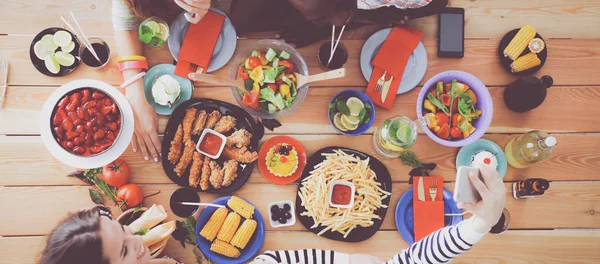 Top view of group of people having dinner together while sitting at wooden table. Food on the table. People eat fast food. — Stock Photo, Image