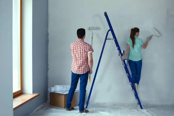 Portrait happy smiling young couple painting interior wall of new house. Young couple — Stock Photo, Image