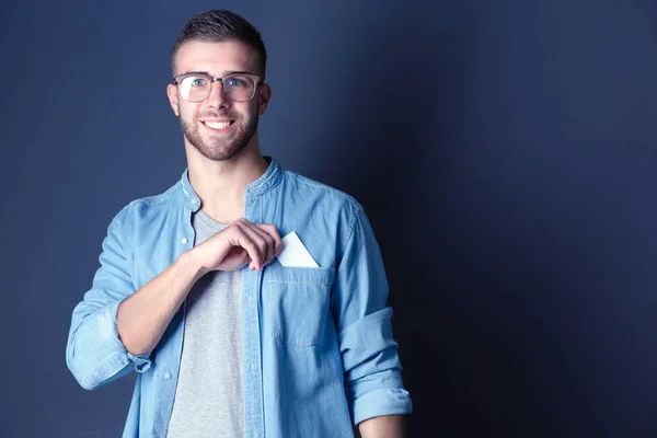 Joven sosteniendo una tarjeta de crédito de pie sobre fondo gris. Joven empresario. —  Fotos de Stock