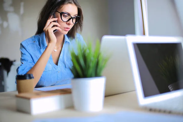 Belle jeune femme d'affaires assise au bureau et parlant sur un téléphone portable. Femme d'affaires — Photo