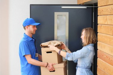 Mavi üniformalı gülümseyen kurye servis konseptine paket kutusu teslim eden teslimatçı. Mavi üniformalı gülümseyen teslimatçı.