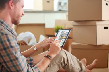 Genç bir çift yeni ev içinde hareket. Oturma ve açma sonra rahatlatıcı. Bir şey üstünde laptop arıyorum. Genç Çift