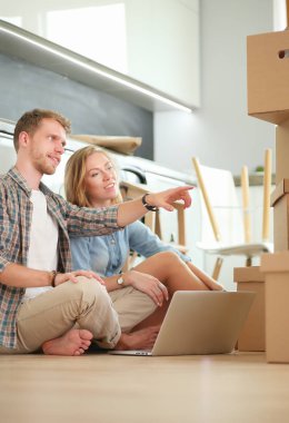 Genç bir çift yeni ev içinde hareket. Oturma ve açma sonra rahatlatıcı. Bir şey üstünde laptop arıyorum. Genç Çift