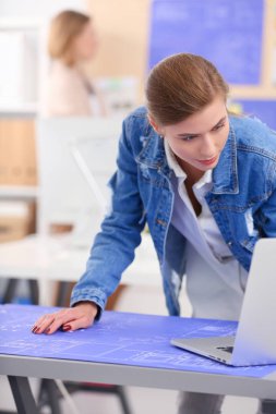 Masanın yanında duran iki genç kadın enstrüman, plan ve dizüstü bilgisayarla.