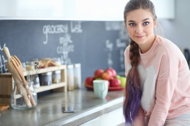 Mutfakta masada oturan genç kadın.