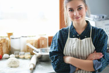Mutfakta sobanın yanında duran genç bir kadın. .