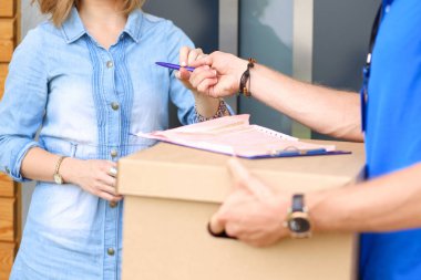 Mavi üniformalı gülümseyen kurye servis konseptine paket kutusu teslim eden teslimatçı. Mavi üniformalı gülümseyen teslimatçı.