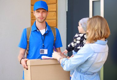 Mavi üniformalı gülümseyen kurye servis konseptine paket kutusu teslim eden teslimatçı. Mavi üniformalı gülümseyen teslimatçı.