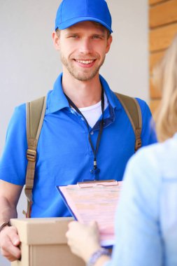 Mavi üniformalı gülümseyen kurye servis konseptine paket kutusu teslim eden teslimatçı. Mavi üniformalı gülümseyen teslimatçı.