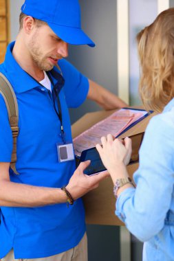 Mavi üniformalı gülümseyen kurye servis konseptine paket kutusu teslim eden teslimatçı. Mavi üniformalı gülümseyen teslimatçı.