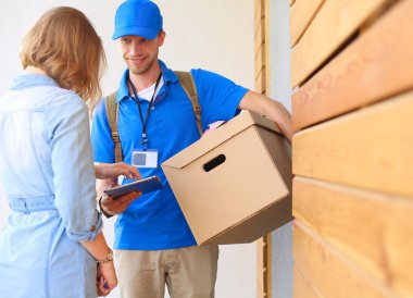Mavi üniformalı gülümseyen kurye servis konseptine paket kutusu teslim eden teslimatçı. Mavi üniformalı gülümseyen teslimatçı.