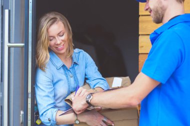 Mavi üniformalı gülümseyen kurye servis konseptine paket kutusu teslim eden teslimatçı. Mavi üniformalı gülümseyen teslimatçı.