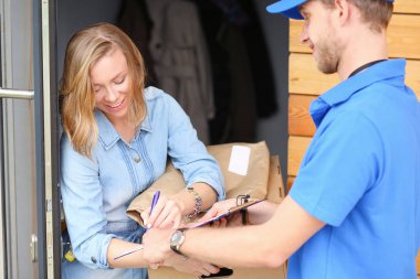 Mavi üniformalı gülümseyen kurye servis konseptine paket kutusu teslim eden teslimatçı. Mavi üniformalı gülümseyen teslimatçı.