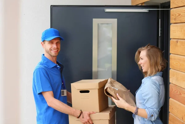 Pengantar senyum dengan seragam biru mengantarkan kotak paket ke penerima konsep layanan kurir. Pria pengiriman senyum dengan seragam biru — Stok Foto