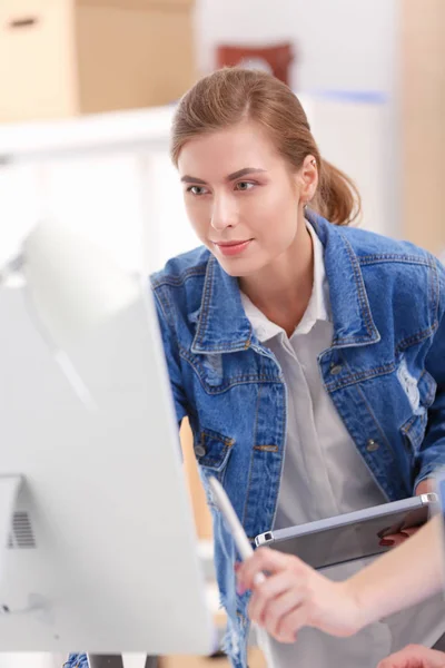 Dos mujeres jóvenes de pie cerca del escritorio con instrumentos, plan y portátil. — Foto de Stock