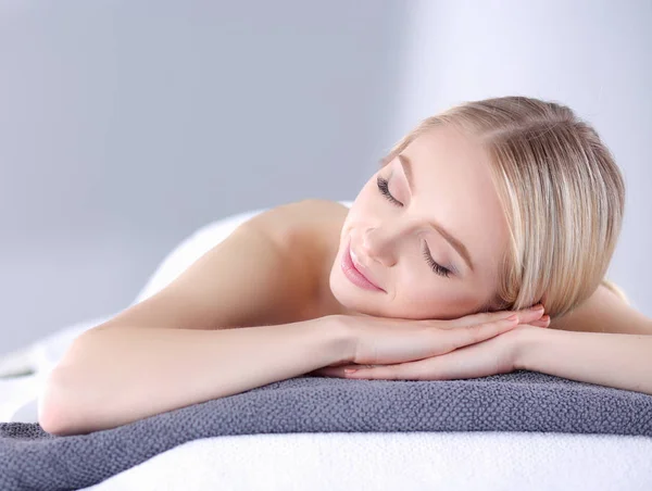 Mujer joven acostada en una mesa de masaje, relajándose con los ojos cerrados. Una mujer. Salón de spa — Foto de Stock