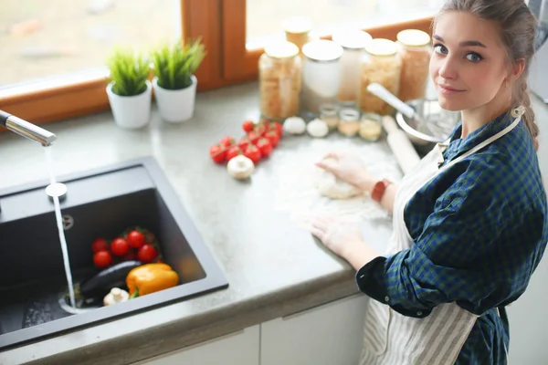 Mujer joven parada junto a la estufa en la cocina . — Foto de Stock