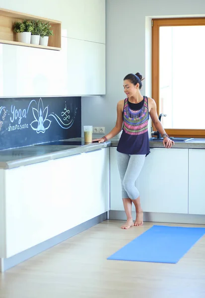 Retrato de una mujer sonriente sosteniendo en su mano una esterilla de yoga mientras estaba de pie en el estudio. Yoga. Una mujer. Bienestar — Foto de Stock