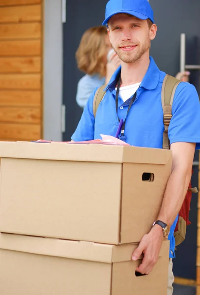 Mavi üniformalı gülümseyen kurye servis konseptine paket kutusu teslim eden teslimatçı. Mavi üniformalı gülümseyen teslimatçı. — Stok fotoğraf